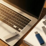 朝日が差し込むデスクに整頓されたノートPCとUSBメモリ