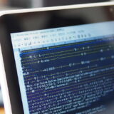 EXEファイルをSakuraエディタで開いたバイナリデータ表示画面。MZやPE、文字化けしたデータが並ぶ実行ファイル内部の様子